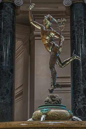 A bronze statue of Mercury with winged sandals, captured in a moment of upward motion, displayed at the National Gallery with water flowing from the base fountain.