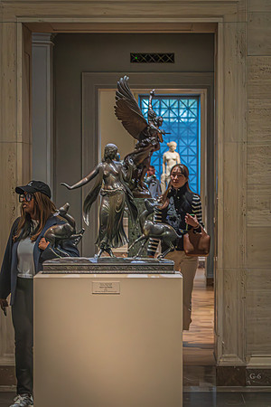 Visitors at the National Gallery observing a dynamic bronze sculpture, with the sculpture appearing to narrate a mythological or historical tale.
