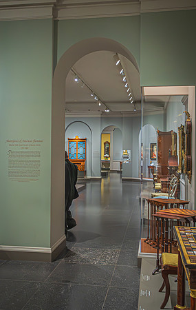 The corridor of the National Gallery's furniture exhibit, displaying historic pieces with detailed craftsmanship.