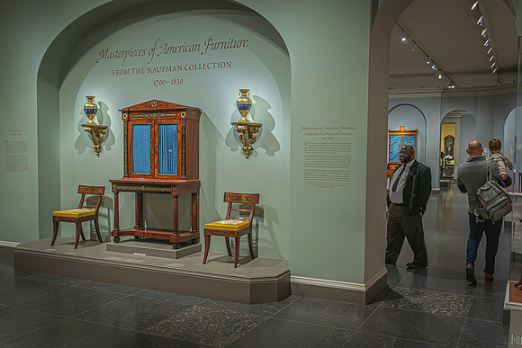 Visitors at the National Gallery view the "Masterpieces of American Furniture" from the Kaufman Collection, showcasing the craftsmanship of the 1700-1830 period.