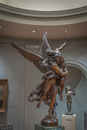 An expressive bronze sculpture with outstretched wings on display at the National Gallery, highlighted by soft lighting.