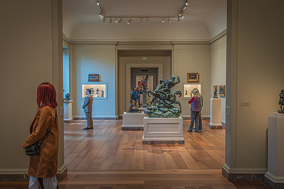 Visitors viewing and interacting with sculptures in a gallery room at the National Gallery, with a large bronze sculpture in the foreground.